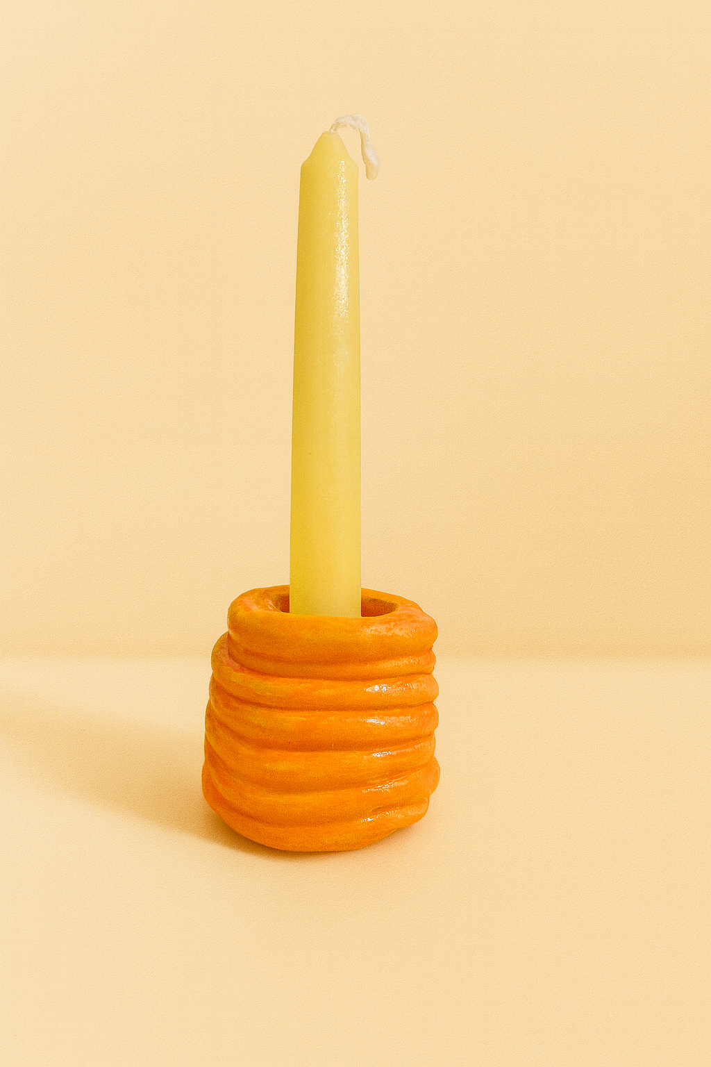 Handmade orange ribbed coil candle holder designed for taper candles, styled as modern aesthetic table decor