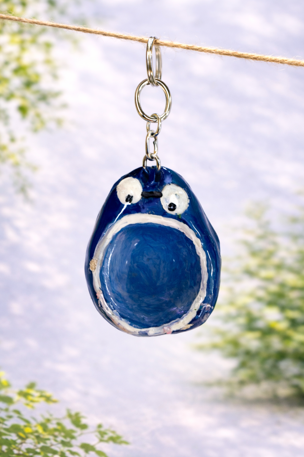 Handmade blue blob creature clay keychain attached to a keyring, designed as a cute kawaii bag charm and quirky accessory
