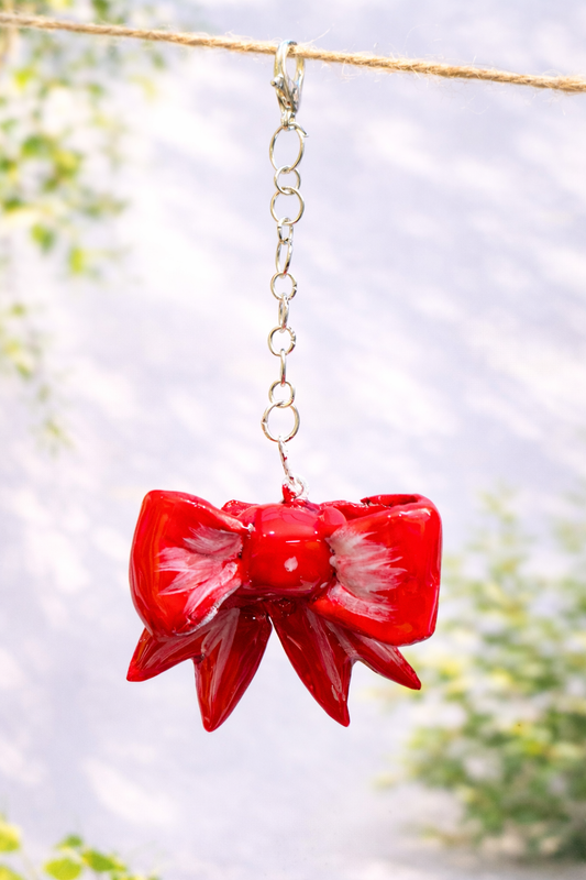 Handmade glossy red bow keychain designed as a coquette bag charm and feminine accessory for handbags and keys